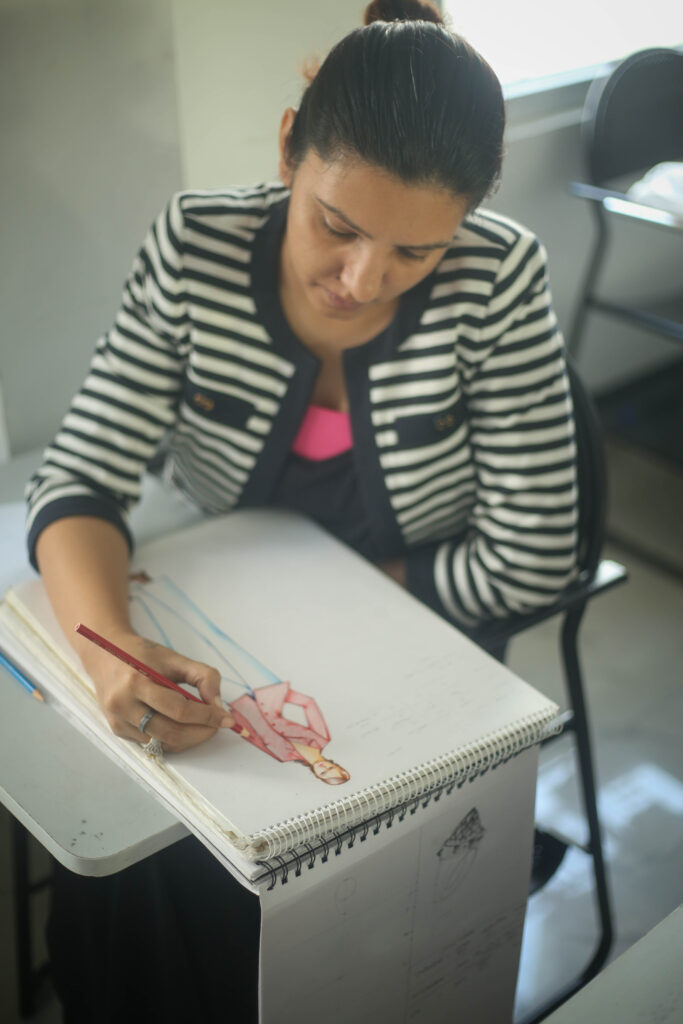 A woman focused on drawing on a piece of paper, showcasing her artistic skills and creativity in a serene environment.